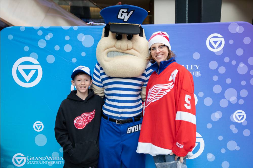 An alumna and her son pose with Louie the Laker at the Detroit Red Wings GVSU Night